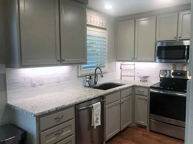 a kitchen with a sink dishwasher a stove and a refrigerator with wooden floor