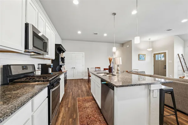 a kitchen with stainless steel appliances granite countertop a sink stove and cabinets