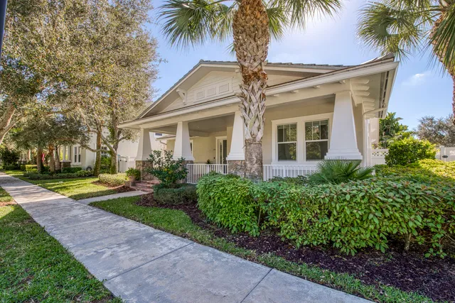 a front view of a house with a garden and palm trees