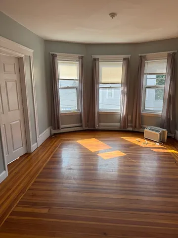 a view of empty room with window and wooden floor
