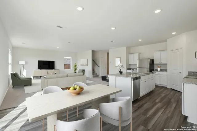 a kitchen with a dining table chairs and white kitchen