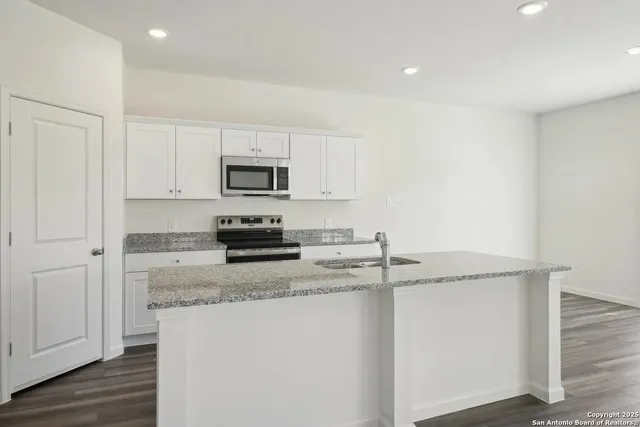 a kitchen with granite countertop a sink stove and microwave