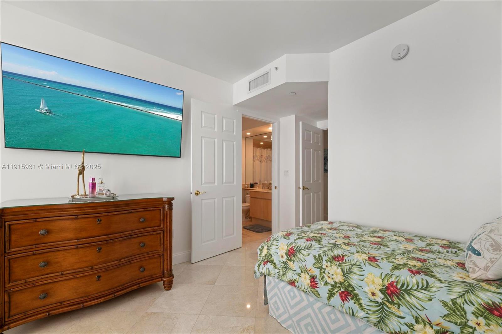18671 Collins Avenue, Unit 1902 Sunny Isles Beach, FL 33160 - Photo 21 of 53 a bedroom with a bed and a mirror on dresser