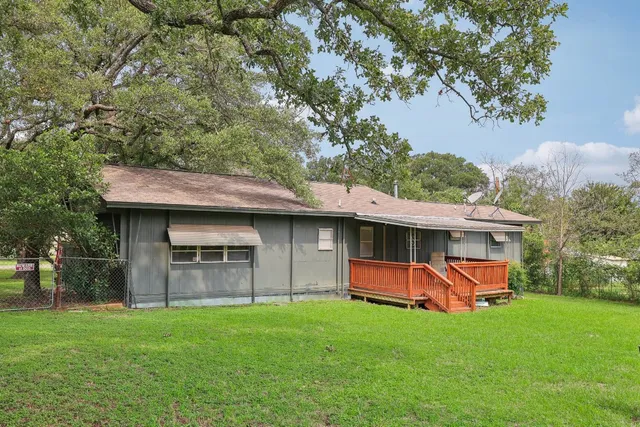 a backyard of a house with table and chairs plants and large tree
