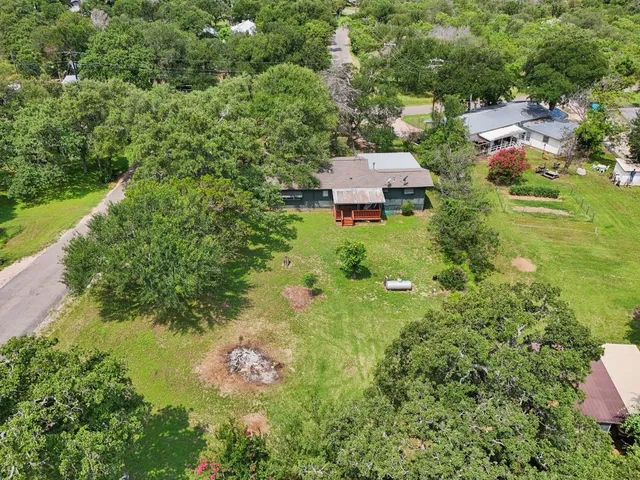 an aerial view of residential house with outdoor space and trees all around