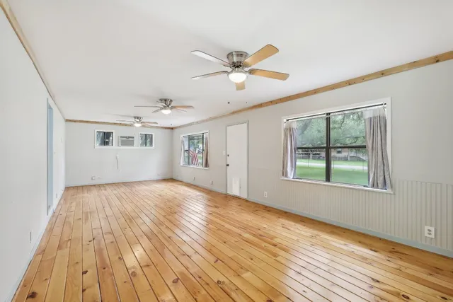a view of empty room with wooden floor and fan