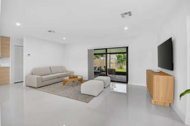 a large white kitchen with sink a stove a dining table and chairs