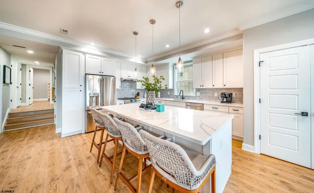 a view of a kitchen with kitchen island a sink stainless steel appliances and cabinets