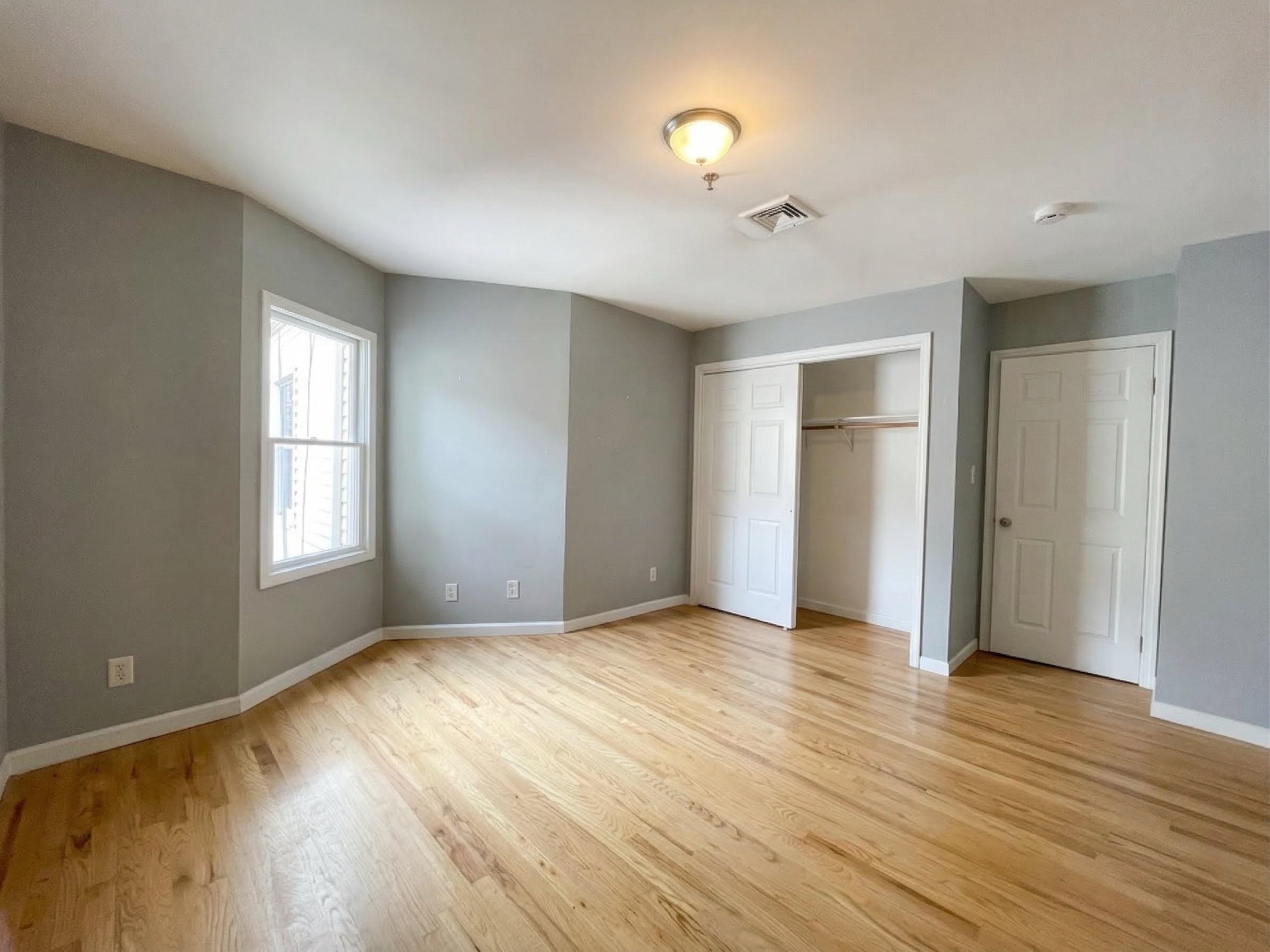 420 6th Street, Unit 3 Union City, NJ 07087 - Photo 5 of 12 a view of an empty room with wooden floor and a window