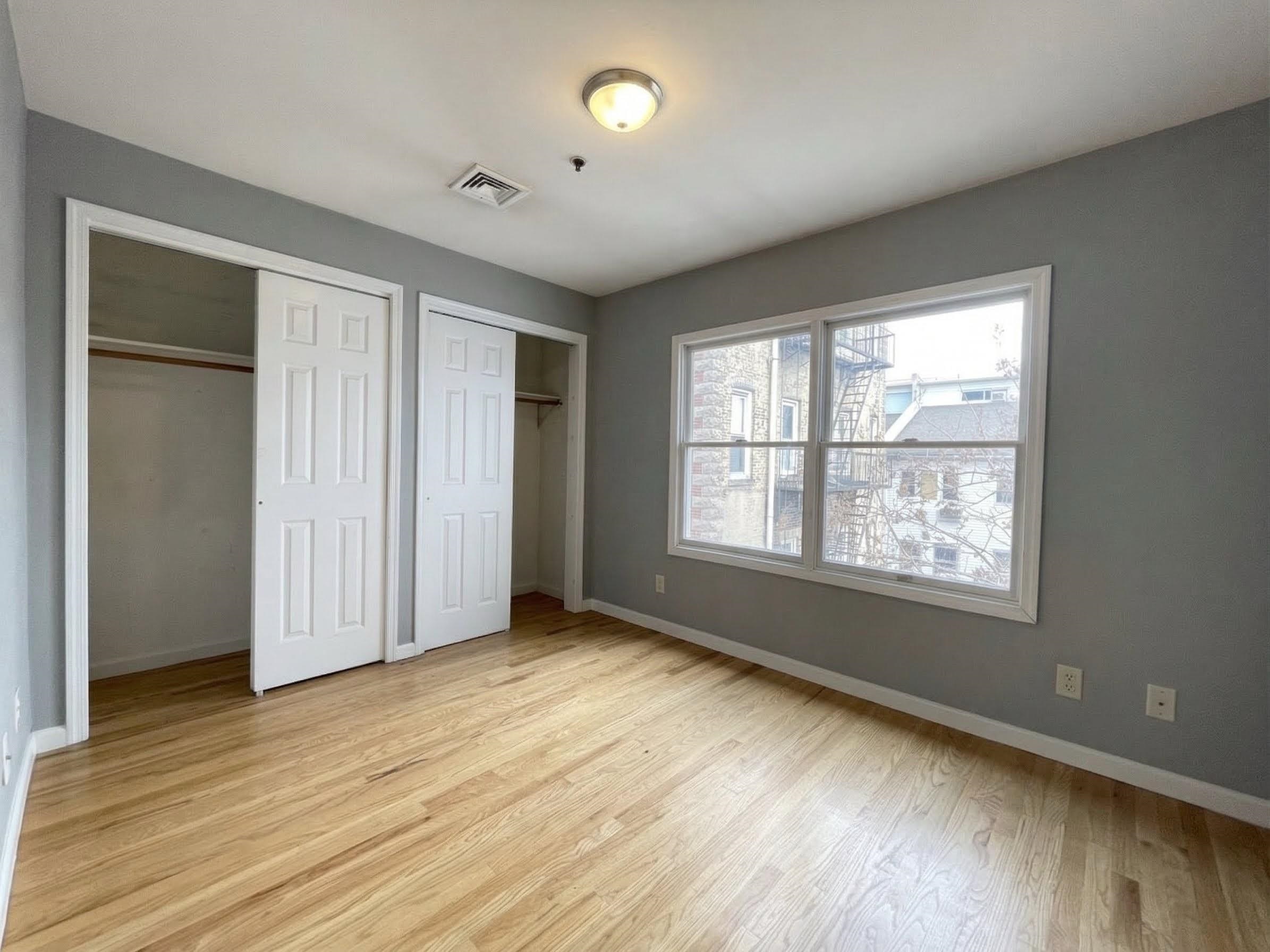 420 6th Street, Unit 3 Union City, NJ 07087 - Photo 8 of 12 a view of an empty room with wooden floor and a window