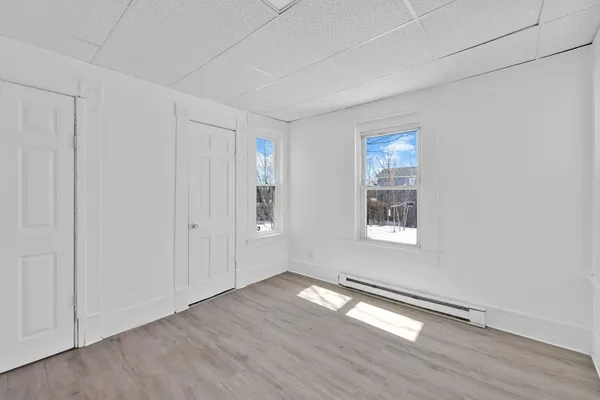 a view of an empty room with wooden floor and a window