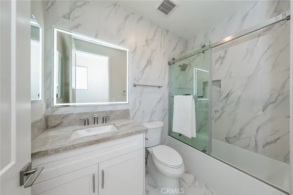 a bathroom with a granite countertop sink toilet and shower