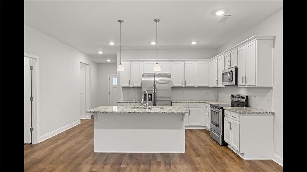 3792 Oak Rdg Drive, Unit HASTINGS Buford, GA 30519 - Photo 16 of 32 a large kitchen with stainless steel appliances kitchen island a large counter top and wooden floors