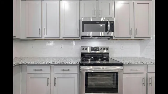 a kitchen with stainless steel appliances granite countertop white cabinets and a stove a sink