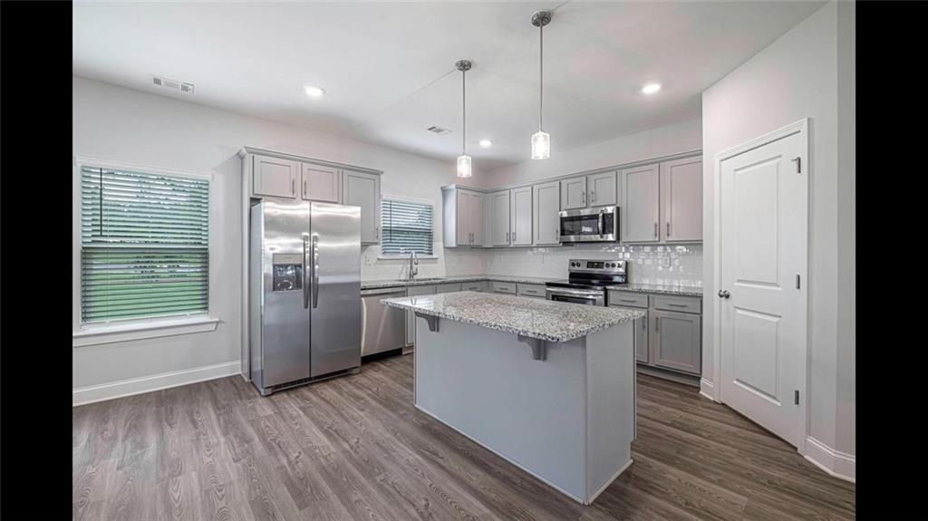3792 Oak Rdg Drive, Unit HASTINGS Buford, GA 30519 - Photo 27 of 32 a kitchen with stainless steel appliances granite countertop a refrigerator a sink dishwasher a stove and white countertops with wooden floor