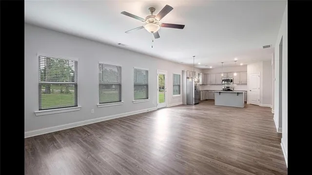 a view of an empty room with a kitchen and wooden floor