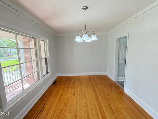 an empty room with wooden floor fireplace and windows