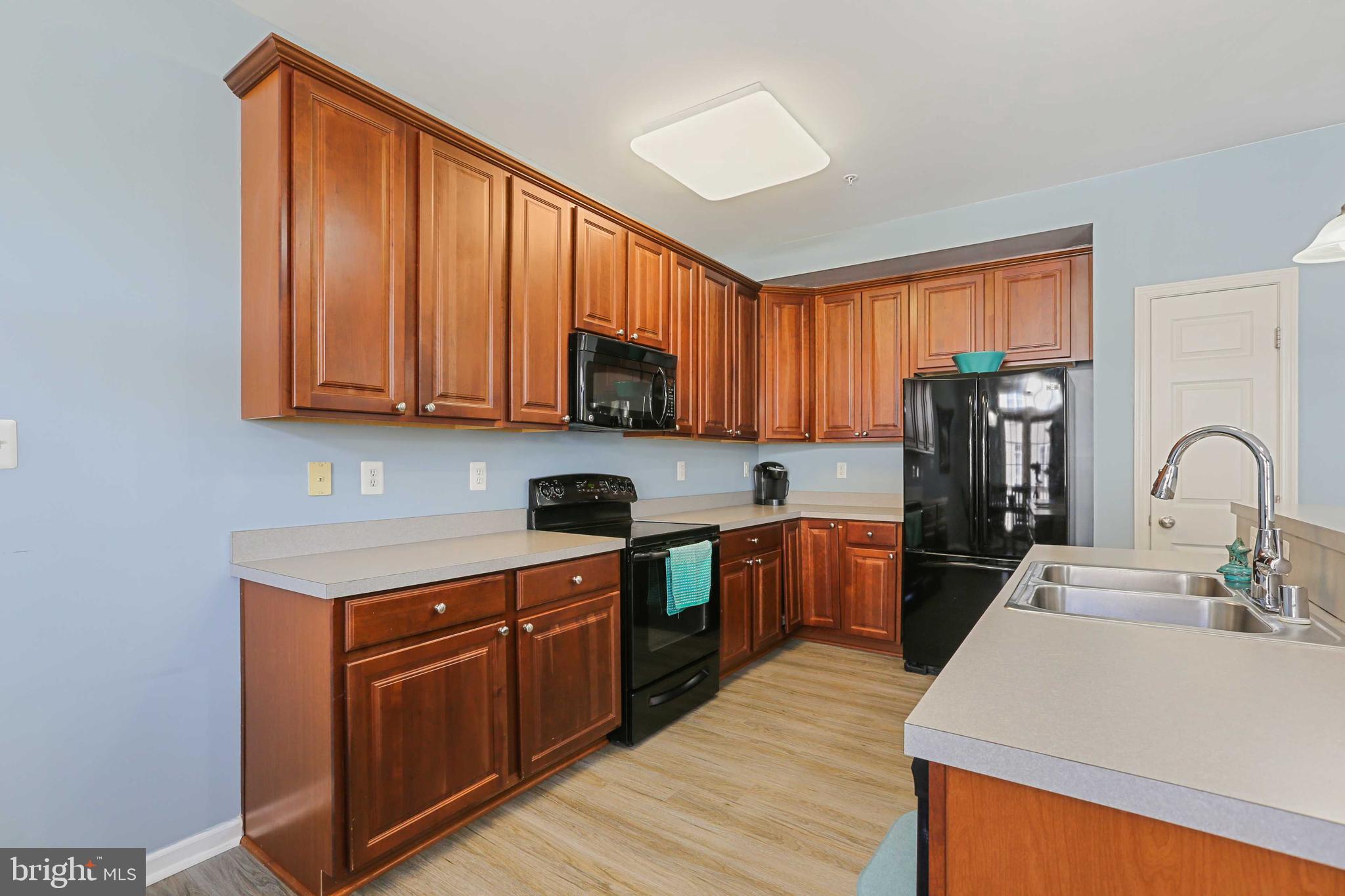 7209 Darby Downs, Unit 7209 Elkridge, MD 21075 - Photo 8 of 19 a kitchen with stainless steel appliances granite countertop wooden cabinets sink and stove top oven