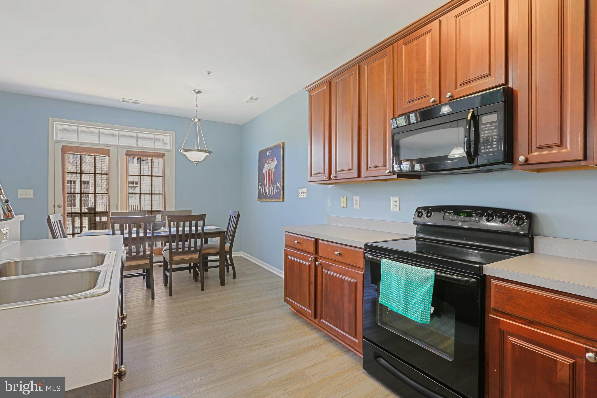 7209 Darby Downs, Unit 7209 Elkridge, MD 21075 - Photo 9 of 19 a kitchen with stainless steel appliances a stove a sink dishwasher and microwave with wooden floor