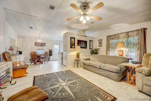 a living room with furniture kitchen view and a large window