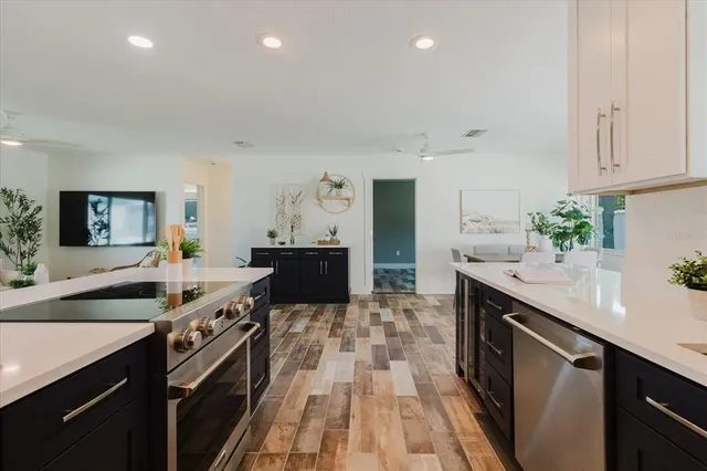 a large kitchen with stainless steel appliances a sink stove and cabinets