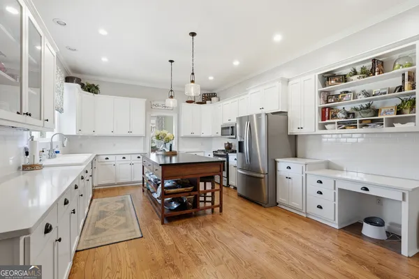 a kitchen with stainless steel appliances granite countertop a refrigerator a sink dishwasher a stove and white cabinets with wooden floor