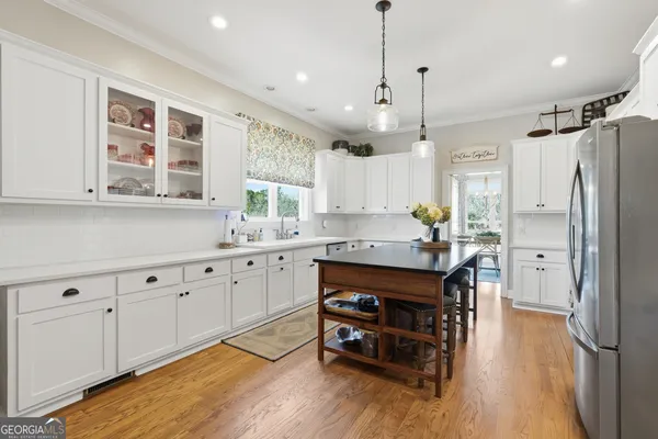a kitchen with stainless steel appliances granite countertop a refrigerator a sink dishwasher a stove and white cabinets with wooden floor