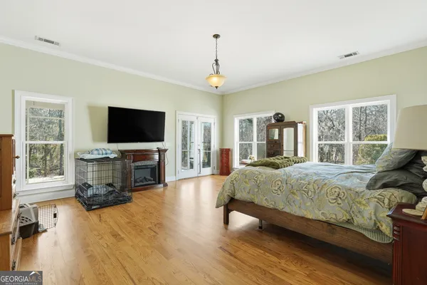 a spacious bedroom with a bed and a flat screen tv on dresser
