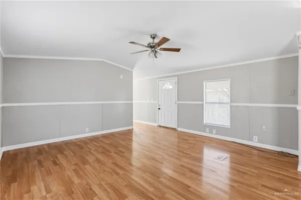 an empty room with wooden floor and windows with ceiling fan