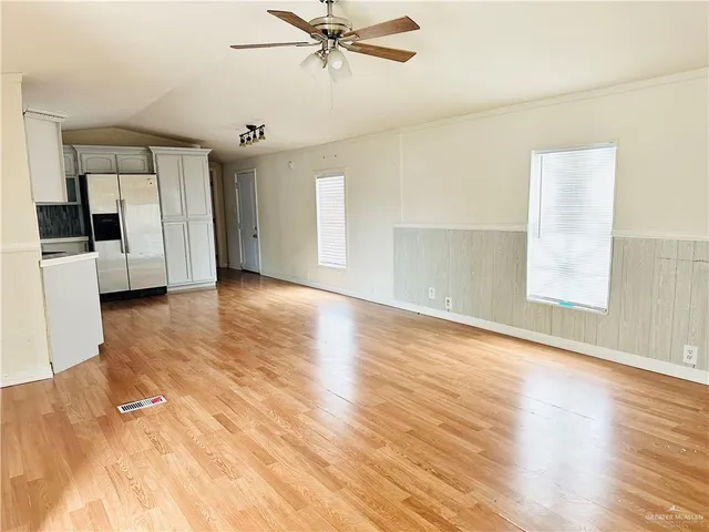 a view of empty room with wooden floor and fan