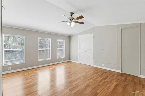 a view of an empty room with a window and wooden floor