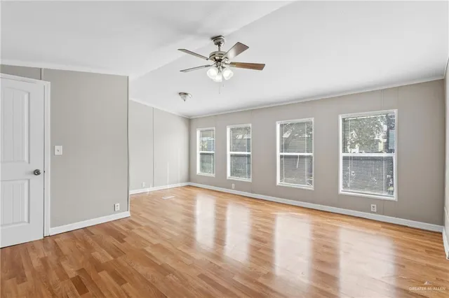 a view of an empty room with a window and wooden floor