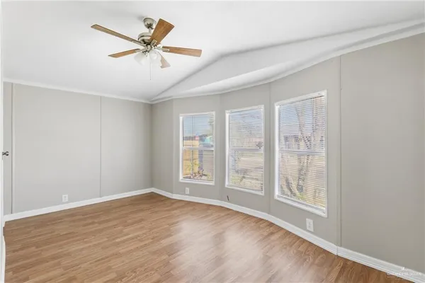 an empty room with wooden floor fan and windows
