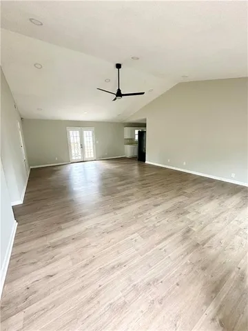 a view of empty room with wooden floor and ceiling fan