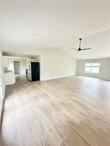 a view of an empty room with wooden floor and a ceiling fan