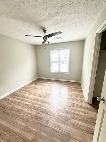 an empty room with wooden floor fan and windows