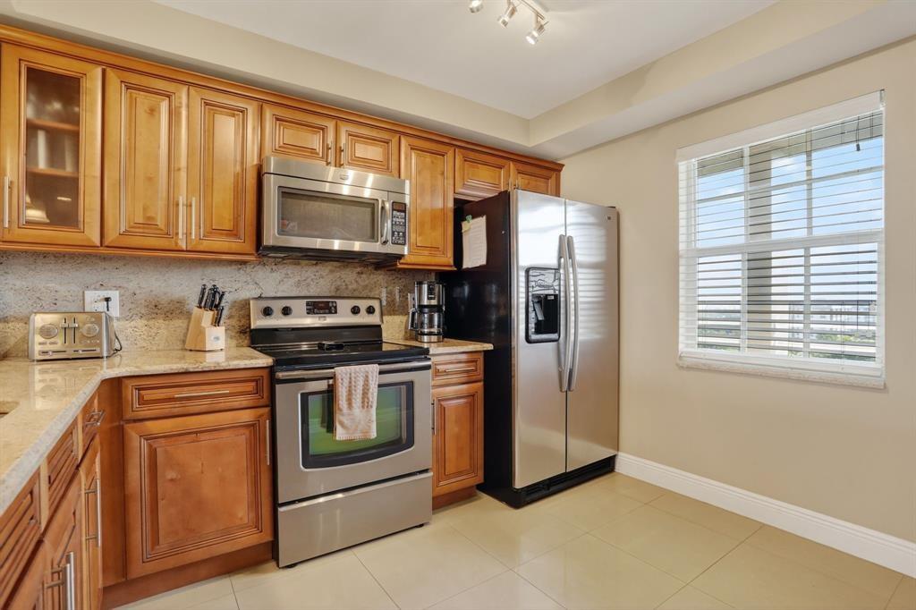 605 Oaks Drive, Unit 1008 Pompano Beach, FL 33069 - Photo 12 of 30 a kitchen with stainless steel appliances granite countertop a stove and a refrigerator