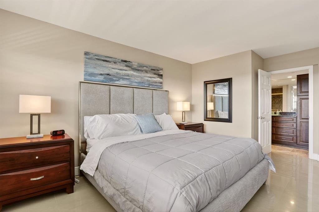 605 Oaks Drive, Unit 1008 Pompano Beach, FL 33069 - Photo 14 of 30 a bedroom with a bed and a lamp on dresser