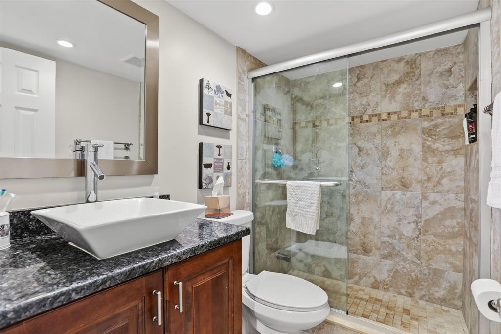 605 Oaks Drive, Unit 1008 Pompano Beach, FL 33069 - Photo 18 of 30 a bathroom with a granite countertop sink a toilet a mirror and shower