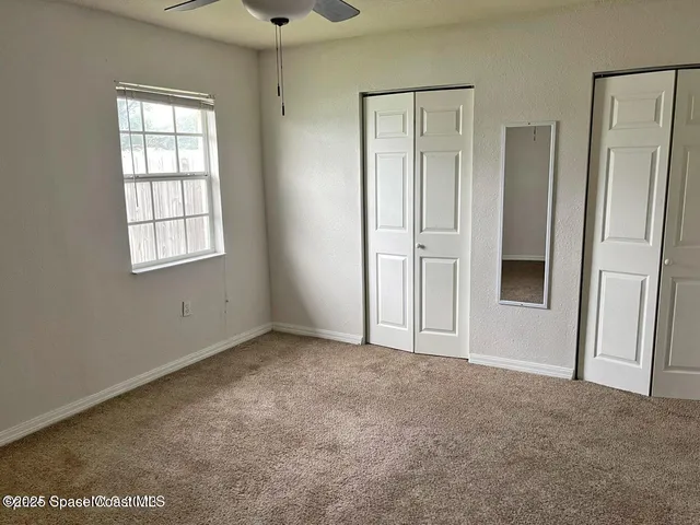 an empty room with a ceiling fan and a window