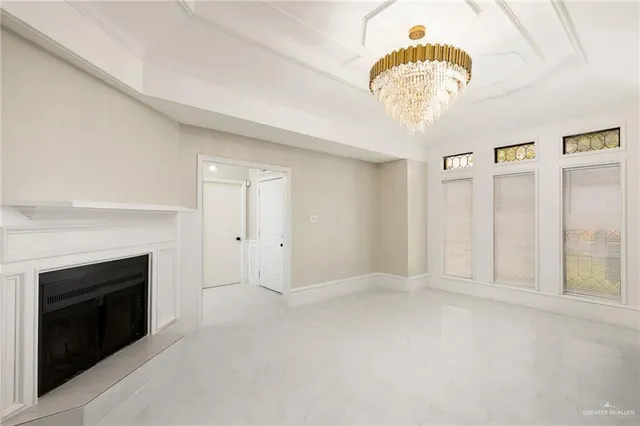 a view of an empty room with a fireplace and a chandelier