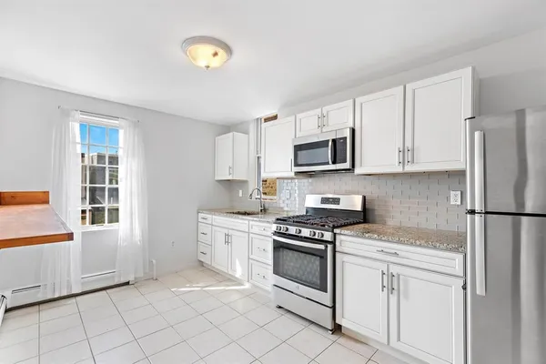 a kitchen with white cabinets and white appliances