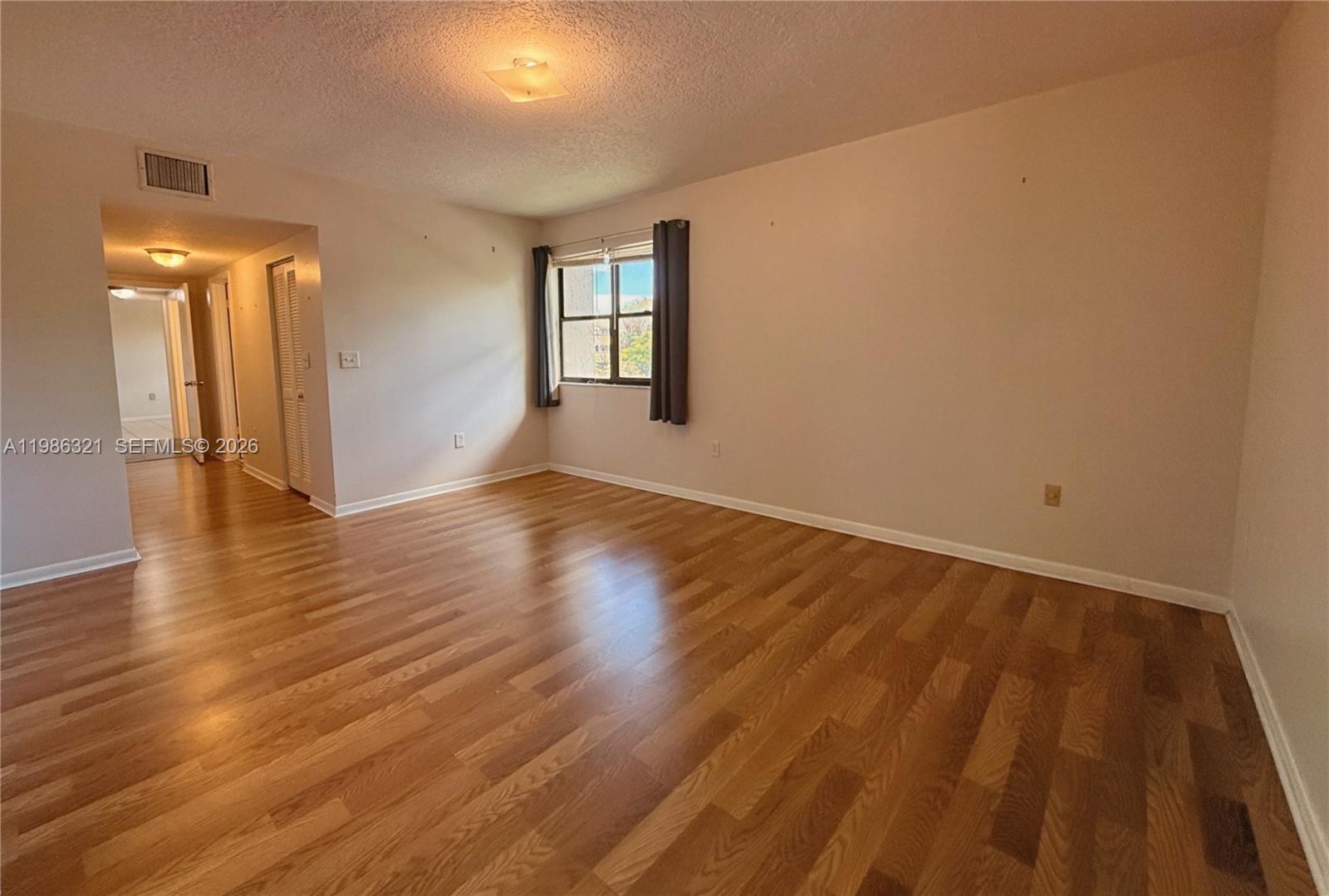 511 Ives Dairy Road, Unit 3016 Miami, FL 33179 - Photo 23 of 72 a view of an empty room with wooden floor and a window