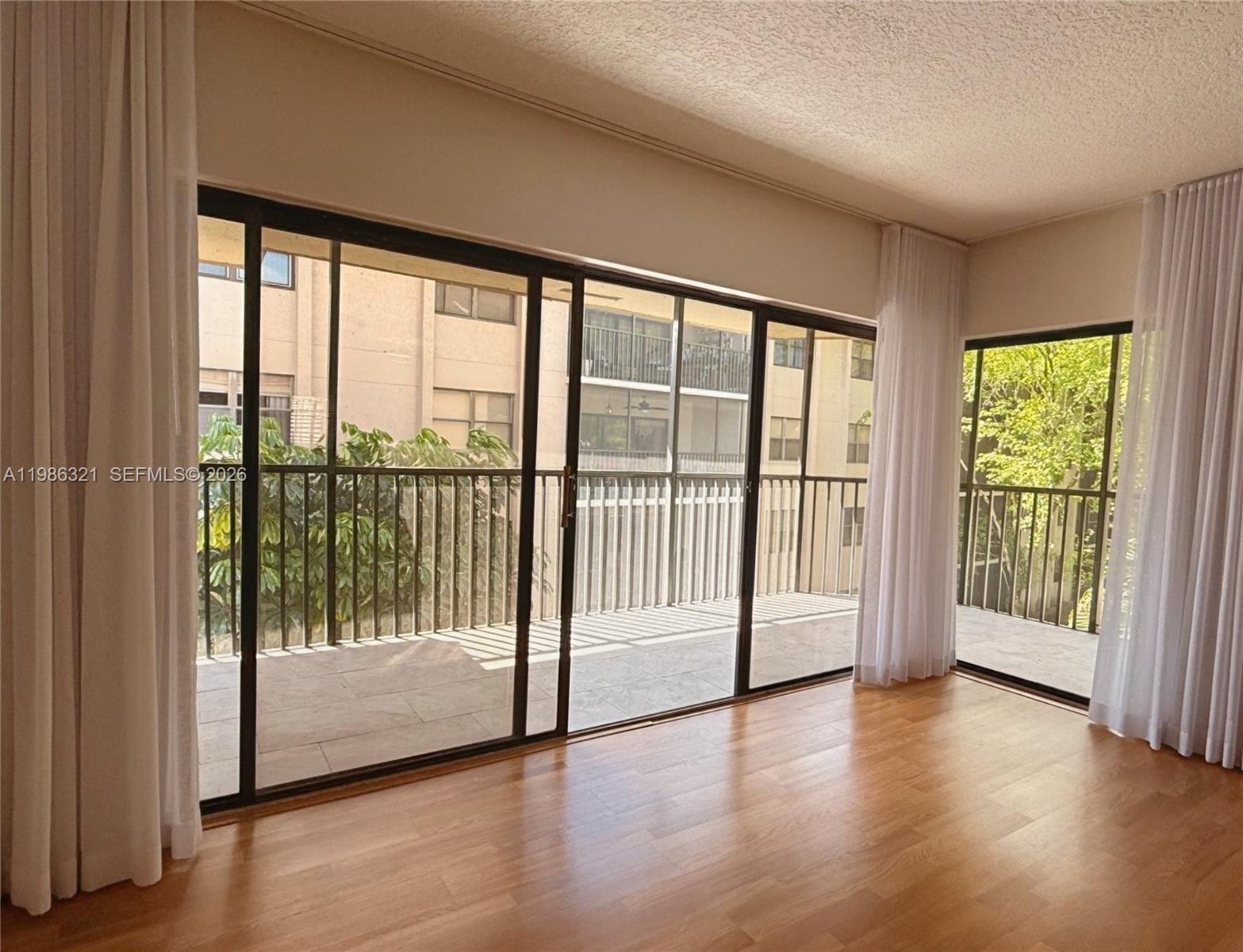 511 Ives Dairy Road, Unit 3016 Miami, FL 33179 - Photo 8 of 72 a view of empty room with wooden floor and floor to ceiling window