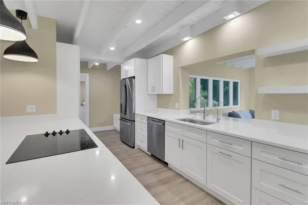 a large kitchen with stainless steel appliances kitchen island a large counter top a sink and a refrigerator