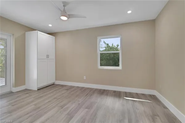 an empty room with wooden floor and windows