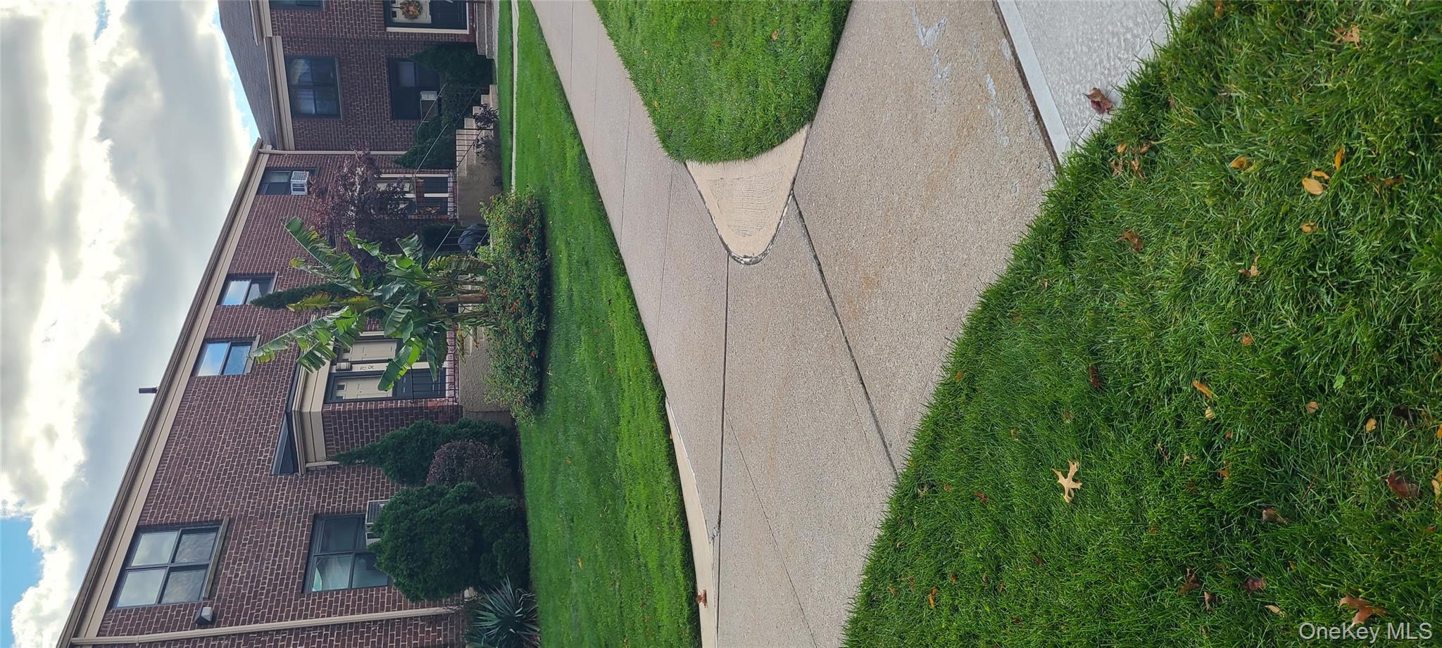 73-54 Springfield Boulevard, Unit 54A2 Queens, NY 11364 - Photo 11 of 11 a view of a house with a yard and a large parking space