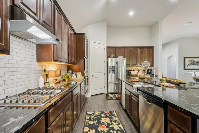 a kitchen with stainless steel appliances granite countertop a stove top oven a sink and dishwasher