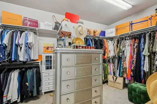 a view of walk in closet with clothes and shoes