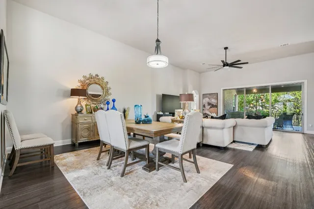 a dining room with wooden floor a chandelier a wooden table and chairs